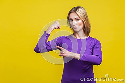 I`m strong. Portrait of proud successful businesswoman pointing at biceps. studio shot isolated on yellow background Stock Photo