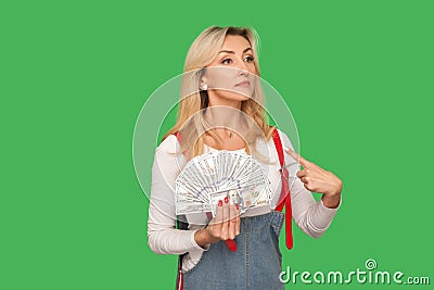 I made lot of money! Portrait of proud rich adult woman holding dollars and pointing at herself, looking arrogant Stock Photo