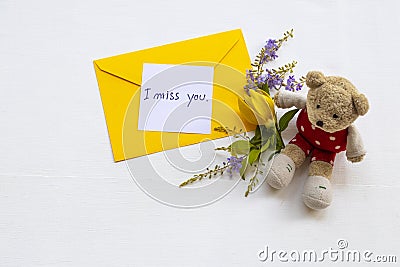 I miss you message card handwriting with yellow envelope, yellow flower ylang ylang and teddy bear Stock Photo