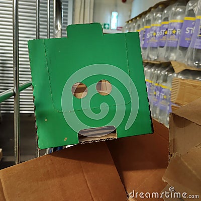 I see faces. Card board box in a warehouse. The holes in the box give the impression the cardboard container has a face. Editorial Stock Photo