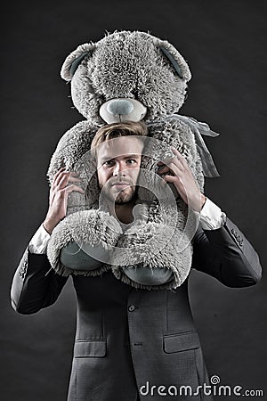 I am so sorry. Man carries giant teddy bear on neck, dark background. Reunion gift concept. Guy calm bearded face with Stock Photo