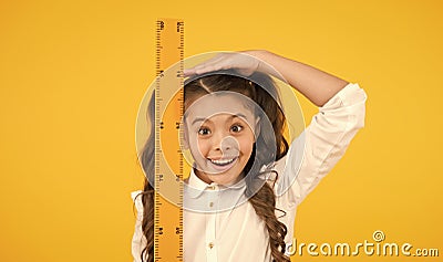 I am still growing. Tall kid. Kid school uniform hold ruler. Pupil cute girl with big ruler. Geometry school subject Stock Photo