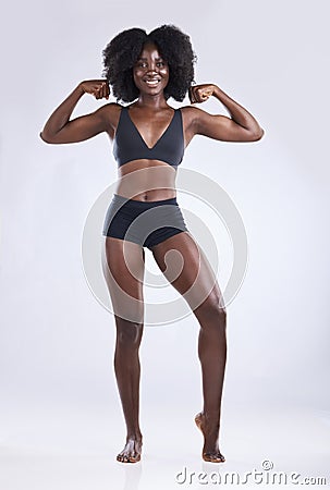 I am a strong and powerful woman. a fit young woman flexing while posing against a studio background. Stock Photo