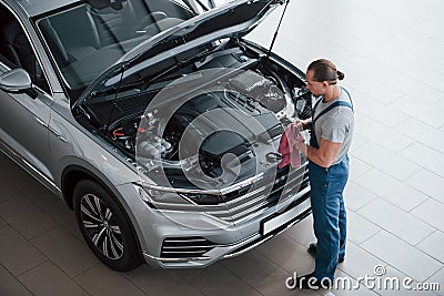 I think I done with this automobile. Man in blue uniform works with broken car. Making repairings Stock Photo