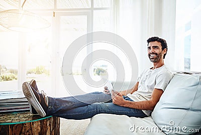 I think I should check out that new series. a man using a digital tablet and relaxing on the sofa at home. Stock Photo