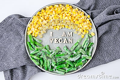 I AM VEGAN text in plate. Veganism, vegetarian healthy lifestyle. Healthy eating vegan, green beans yellow corn Stock Photo