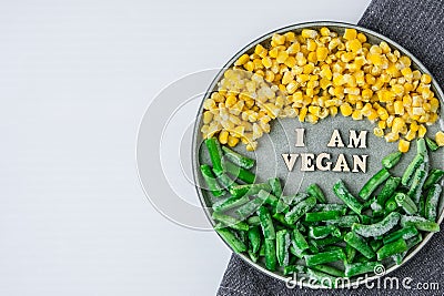 I AM VEGAN text in plate. Veganism, vegetarian healthy lifestyle. Healthy eating vegan, green beans yellow corn Stock Photo