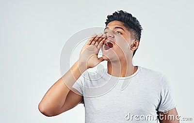 I want everyone to hear. Studio shot of a young man shouting while standing against a white background. Stock Photo