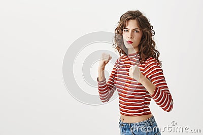 I will knock you down with my left fist. Serious and confident stylish woman raising hands in defense, standing in Stock Photo
