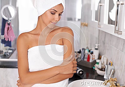 I wish I could stay in this towel all day. a beautiful young woman standing in the bathroom in a towel. Stock Photo