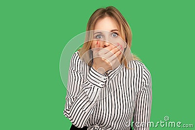 I won`t say anyone! Frightened blond girl covering her mouth with arm and looking at camera with scared big eyes Stock Photo