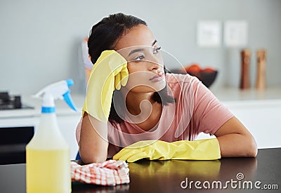 I wonder if ill ever finish cleaning. a young woman taking a break form cleaning her kitchen. Stock Photo