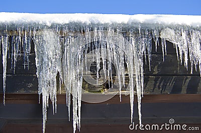 Icicles hanging on barn after cold winter night. Stock Photo