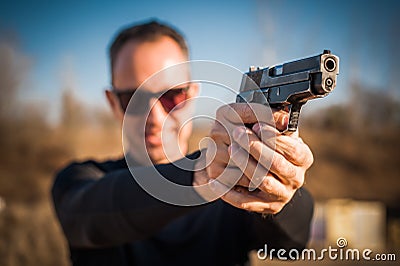 Police agent and bodyguard pointing pistol to protect from attacker Stock Photo