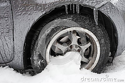 Ice buildup and icicles on a car and close-up of a frozen wheel Stock Photo