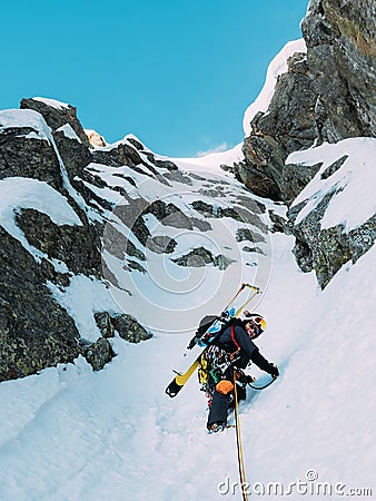 Ice climbing: mountaineer on a mixed route of snow and rock during the winter Stock Photo