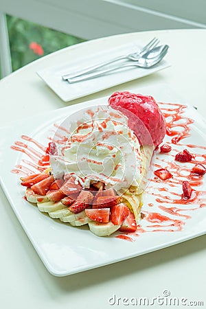 Ice cream strawberry crepe dessert on white dish wood table in c Stock Photo