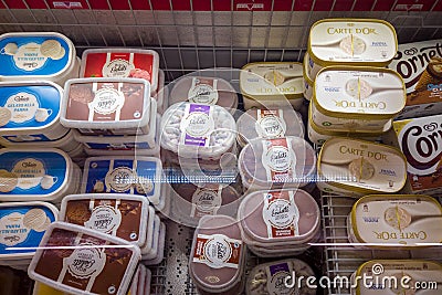 Ice creams of different flavors in plastic tubs in refrigerated counter Editorial Stock Photo