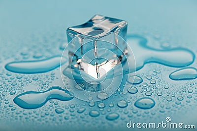 Ice cube with water drops on a blue background. The ice is melting Stock Photo