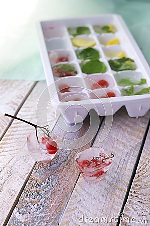 Ice cubes with mint, lemon and red berries in a tray for making drinks Stock Photo