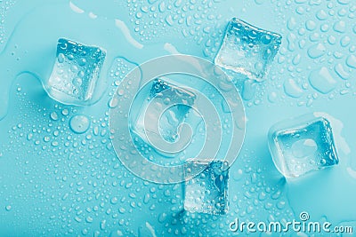 Ice cubes with water drops scattered on a blue background, top view Stock Photo