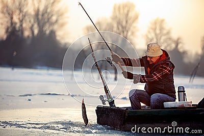 Ice fishing on frozen lake- smiling fisherman catch fish pike Stock Photo