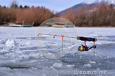 Ice fishing pole with pink real and pole sitting on ice waiting for fish Stock Photo