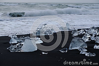 Crystal Clear and Blue Ice Floes on a Black Sand Beach on the Iceland Coast in heavy surf Stock Photo