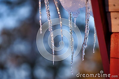 Ice hems on a roof in cold winter melting on sunny day Stock Photo