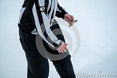 Ice hockey linesman holding a whistle and watching the game Stock Photo