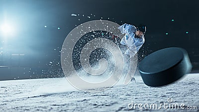 Ice Hockey Rink Arena: Professional Player Shooting the Puck with Hockey Stick. Focus on 3D Flying Stock Photo
