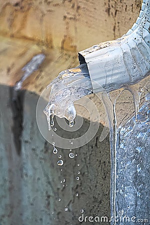 Ice melting though an eavestrough in spring Stock Photo