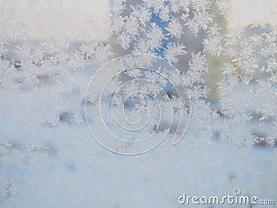 Ice patterns on the window. Beautiful curls and crystals on glass. Outside the window there is a blue winter sky, snow and a city Stock Photo