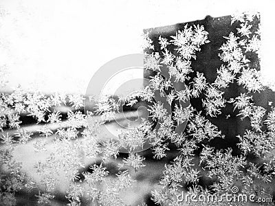 Ice patterns on the window. Beautiful curls and crystals on glass. Outside the window there is a blue winter sky, snow and a city Stock Photo