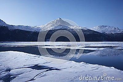 Ice- and snow-covered shores of clean mountain lake Stock Photo