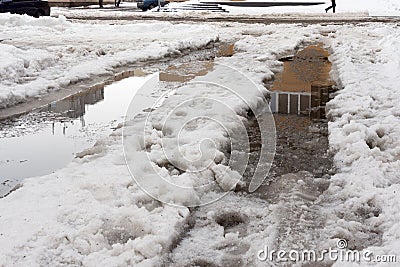Ice and snow in puddles spring. Thaw after winter in the city. Stock Photo