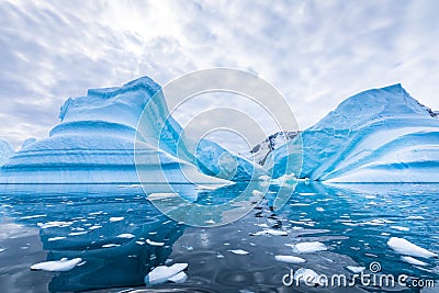 Iceberg in Antarctica floating in the sea, frozen landscape with massive pieces of ice reflecting on water surface, Antarctic Stock Photo