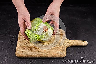 Iceberg lettuce crisphead lettuce in hands on wooden cutting board Stock Photo