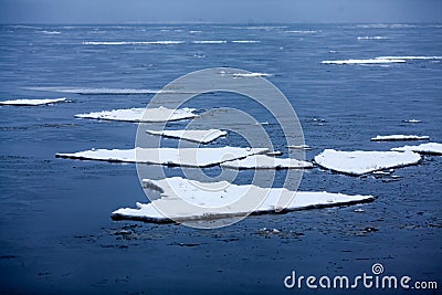 Icebergs in the water. Flat white ice floes floating in the blue sea. Stock Photo