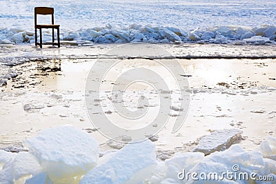 Icebound chair near ice hole in frozen lake Stock Photo