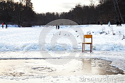 Icebound chair near opening water in frozen lake Stock Photo