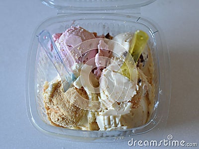 Icecreams balls in plastic box with colorful spoons Stock Photo