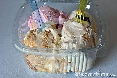 Icecreams balls in plastic box with colorful spoons Stock Photo