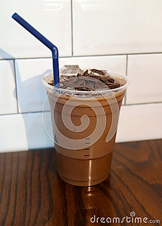 Iced chocolate topped with chocolate chunk in takeaway glass isolated on wooden table Stock Photo