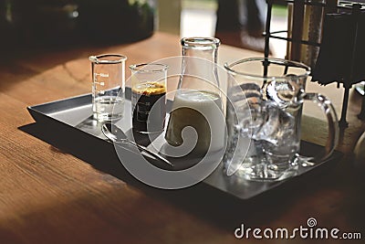 iced coffee latte, ice cubes espresso milk and sweet syrup served in various test tubes on wooden table in morning cafe Stock Photo