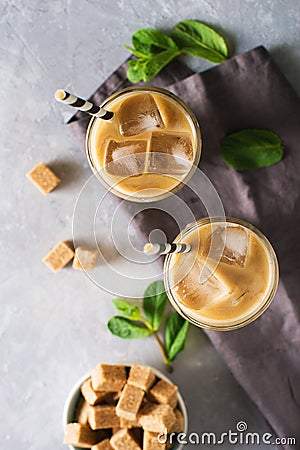 Iced coffee in tall glasses with cream and pieces of sugar, mint Stock Photo