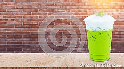 Iced matcha green tea latte frappuccino with milk foam in takeaway cup on wooden table, Summer drinks with iced Stock Photo