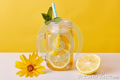 Iced tea with lemon slices and mint, glass pitcher with citrous refreshing summer cocktail and drinking straw on table decorated Stock Photo