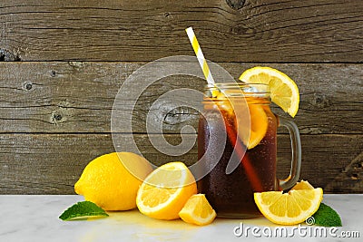 Iced tea in a mason jar glass with lemons, side view against dark wood Stock Photo