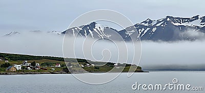 Hrisey Island under the snowy mountains and fog in Eyjafjordur, Iceland Stock Photo